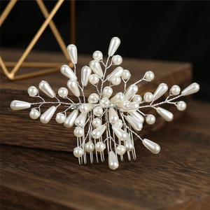 Détail d'un peigne à cheveux de mariée fait main avec des perles blanches et fil argenté