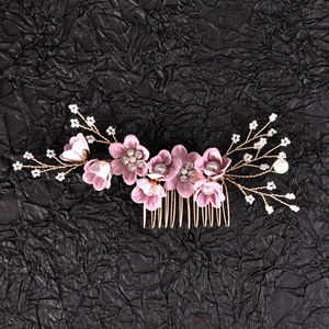 Detail view of pink fabric flowers and pearls on a gold-tone bridal hair comb