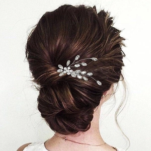 Elegante pettine per capelli da sposa argento con strass e fiori su un'acconciatura raccolta