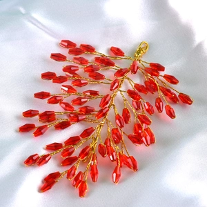Detail of handmade red crystal branch hair accessory with gold wire on white silk