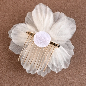 Détail d'un peigne à cheveux de mariée avec fleurs en tissu blanc et dents en métal doré