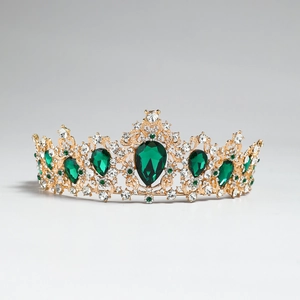 Detail view of ornate gold crown featuring emerald green crystals and sparkling diamonds