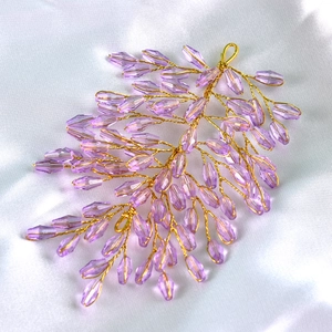 Macro shot of handmade gold wire hair accessory with purple faceted crystal beads