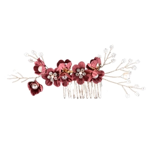 Detailed macro view of deep red fabric flowers with pearls on a golden metal hair comb