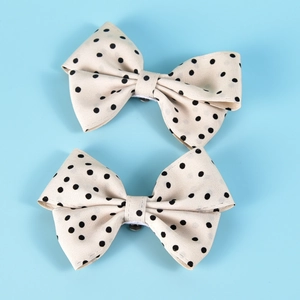 Close-up of beige polka dot bow shoe clips with black dotted fabric and metal fasteners