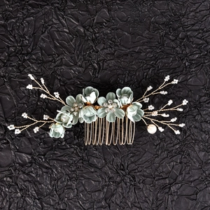 Detail view of handcrafted silk flowers with crystal centers and pearls on a gold hair comb