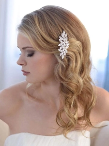 Détail d'un peigne de mariée argenté avec feuilles en cristal sur une coiffure de fête
