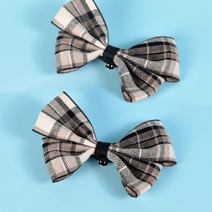 Detailed view of two checkered bow shoe clips with black ribbon centers and metal fasteners