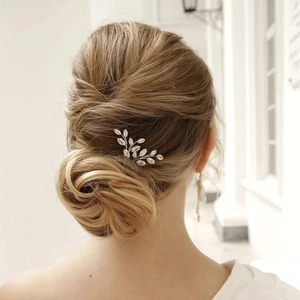 Detail of silver bridal hair pins with leaf design and rhinestones in a low bun hairstyle
