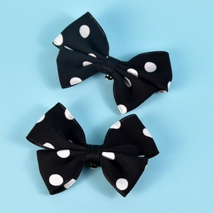 Detail of two black and white polka dot bow shoe clips on a bright blue background