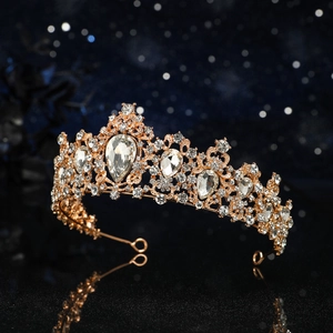 Close-up of golden crown with teardrop rhinestones on reflective black surface
