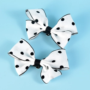 Detailed close-up of white fabric shoe clips with black polka dots and metal fasteners