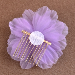 Détail macro de la fleur en mousseline violette et des dents du peigne en métal doré