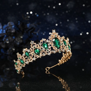 Close-up of royal baroque gold crown with sparkling green crystals and emerald droplets