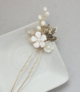 Dettaglio di un fermaglio per capelli da sposa con fiori smaltati, perle e foglie d'oro