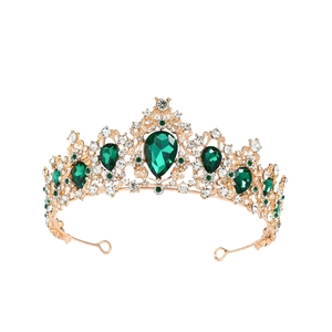 Close-up of golden crown with teardrop green gemstones and sparkling rhinestones