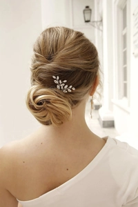 Close-up of elegant silver leaf bridal hair comb with crystals worn in a low bun