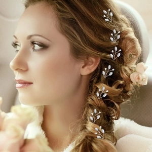 U-shaped bridal hair pins with silver leaves and pearls worn in an elegant side braid
