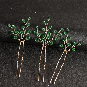 Détail de trois épingles à cheveux en branches dorées avec perles vertes pour mariées