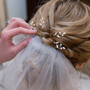 Detailed view of silver bridal hair pins with pearls and rhinestones in a braided hairstyle