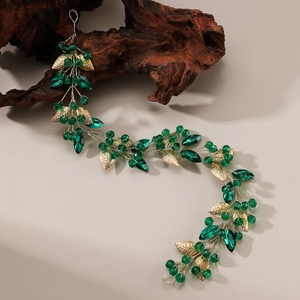 Détail des cristaux vert émeraude et feuilles dorées sur un bandeau fait main flexible