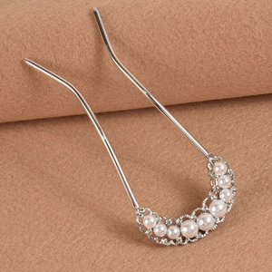 Elegant U-shaped silver hairpin with pearls and rhinestones on a brown fabric background