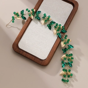 Détails de cristaux émeraude et feuilles de métal doré sur un bandeau fait main