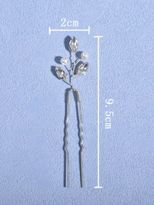 Macro detail of U-shaped silver hair pin with white pearls and crystal leaves