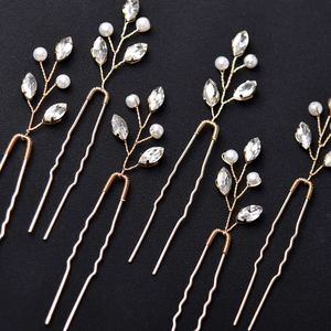 Detail of six golden U-shaped hair pins with white faux pearls and clear rhinestones