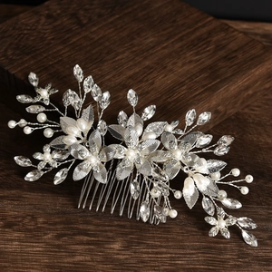 Silver bridal hair comb with elegant crystal flowers and white pearls on dark wood base