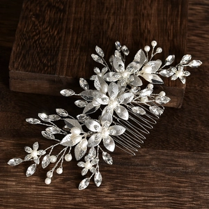 Silver bridal hair comb with elegant flowers, pearls, and crystals on dark wood background