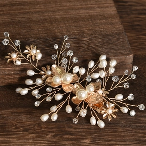 Handmade golden bridal hair comb with elegant white pearls and crystals on dark wood