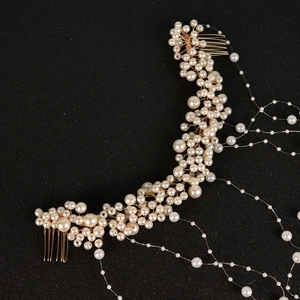 Detail of bridal hair comb with pearls and golden tassels on a black background