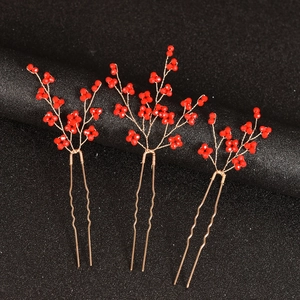 Détail de trois épingles à cheveux en perles rouges en forme de U avec branches dorées