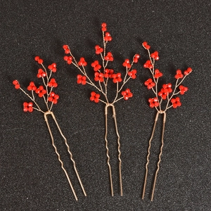 Détail de trois épingles à cheveux de mariée avec perles rouges et branches dorées