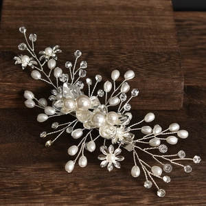 Detail of bridal hair pin with pearls, crystals, and silver flowers on wood surface