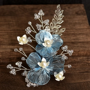 Exquisite bridal hair clip featuring blue petals, white pearls, and silver leaves for weddings