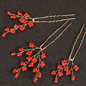 Détail d'épingles à cheveux de mariée en forme de U avec cristaux rouges et fil doré