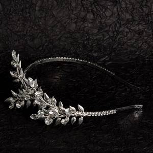 Serre-tête de mariée argenté avec feuilles de cristal et strass sur un fond noir texturé