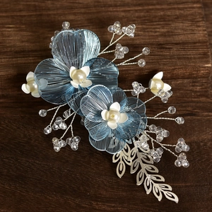 Close-up of handmade bridal hair clip with ice blue petals, pearls, and crystal branches