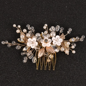 Détail de peigne de mariée avec fleurs en céramique blanche, perles et feuilles dorées
