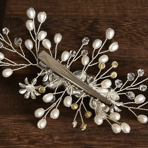 Close-up of handmade bridal hair clip with white pearls, crystals and alloy flowers
