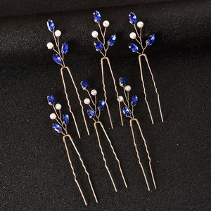 Detailed view of U-shaped hair pins with blue crystals and pearls in gold branch design