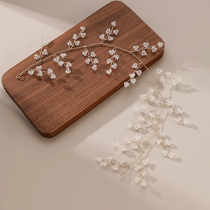 Vue détaillée du bijou de tête de mariée fait main avec cristaux et fil doré sur bois
