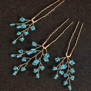 Détail de trois épingles à cheveux en U avec perles de cristal bleu et fils dorés