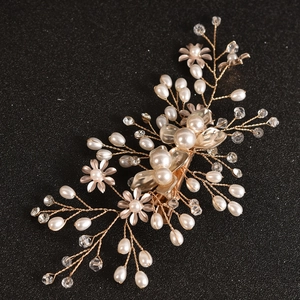 Close-up of handmade bridal hair clip with gold flowers, pearls and crystal branches