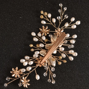 Macro shot of bridal pearl hair clip back showing golden duckbill clip and wire craft