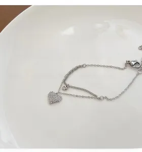 Detail of silver double-layered bracelet featuring a sparkling zircon heart and snake chain