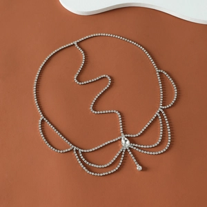 Silver rhinestone bridal forehead chain with teardrop pendant on brown background