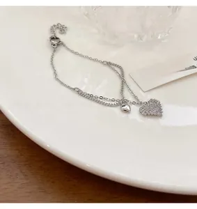 Detail of silver double-layer heart bracelet with sparkling cubic zirconia on white ceramic tray